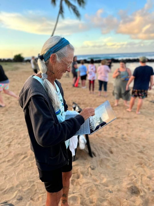 An old lady using a laptop at beach